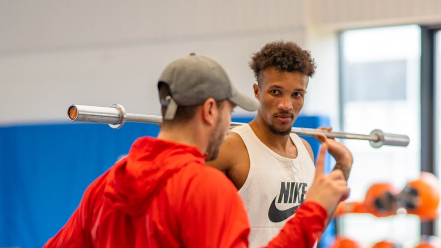 Préparateur physique Odysium face à un athlète professionnel, barre sur les épaules