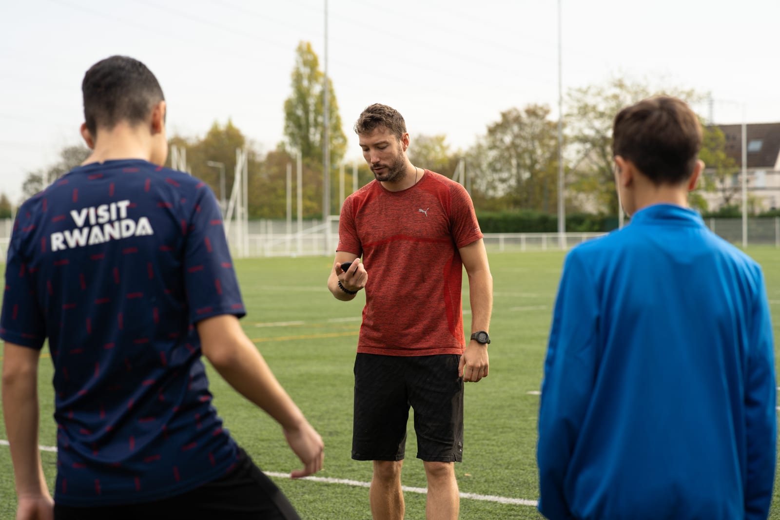 Le coach chronomètre deux jeunes athlètes sur le terrain