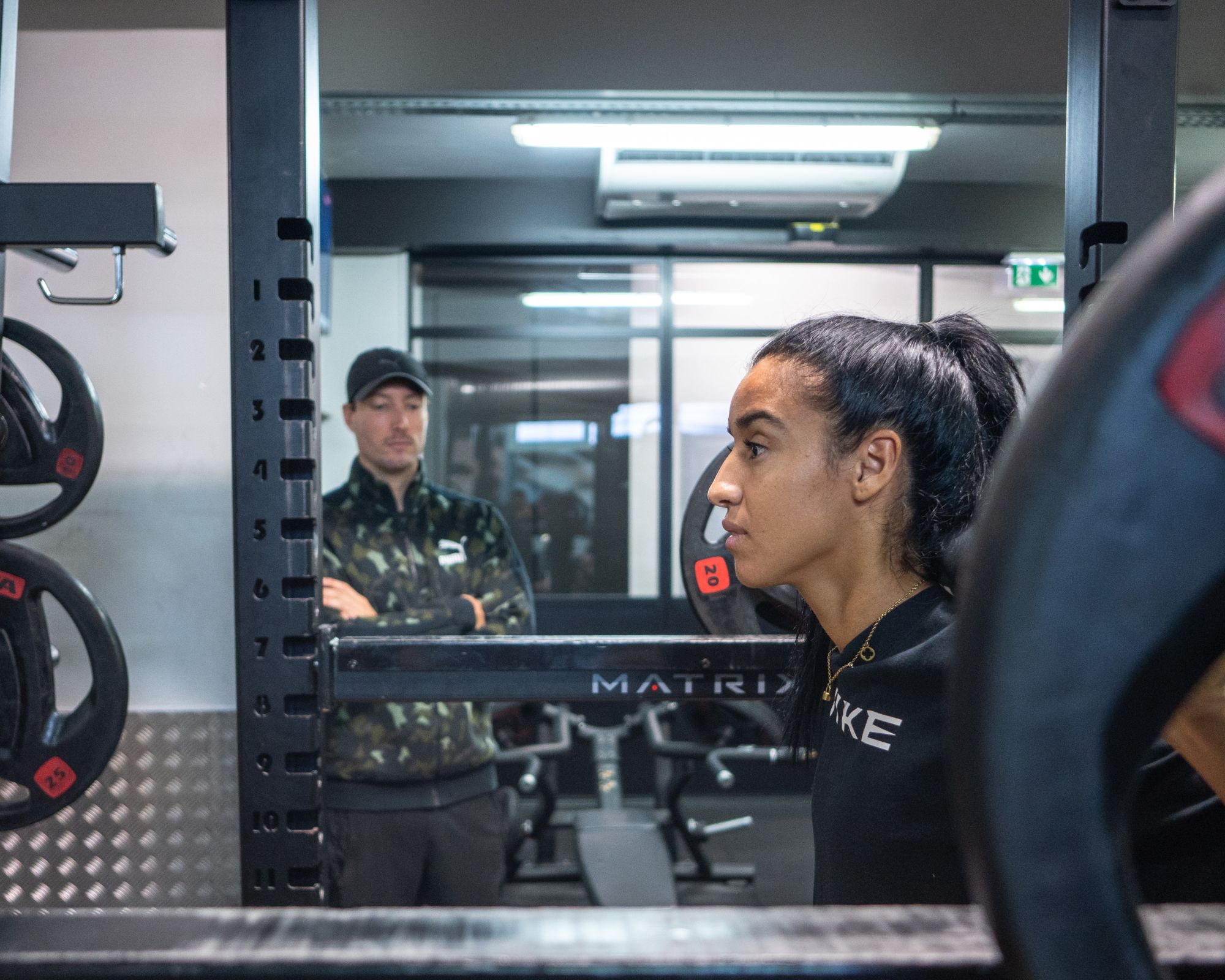 Athlète sous la barre, le préparateur observe