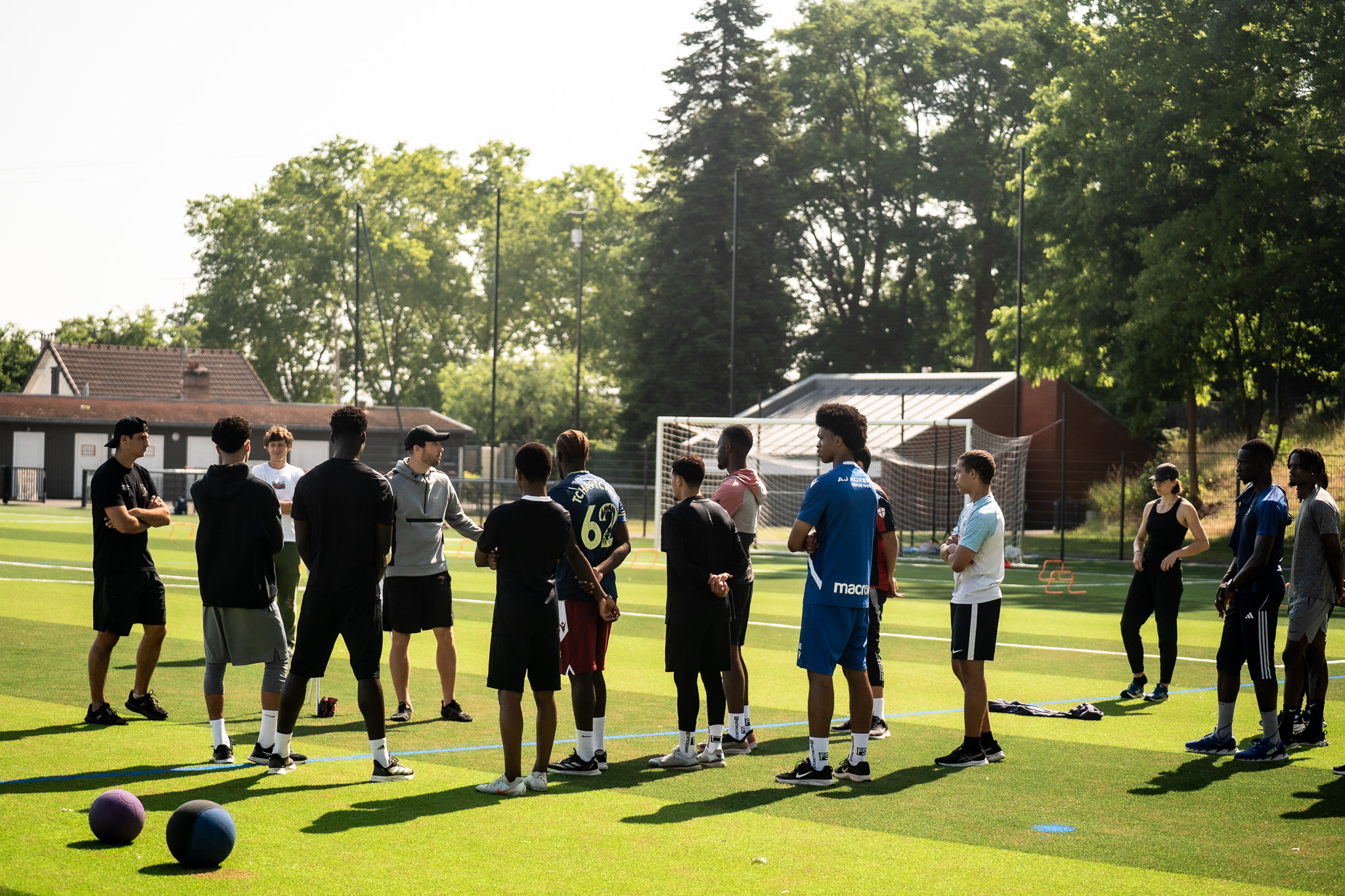 Groupe de sportifs réunis autour du coach avant la séance